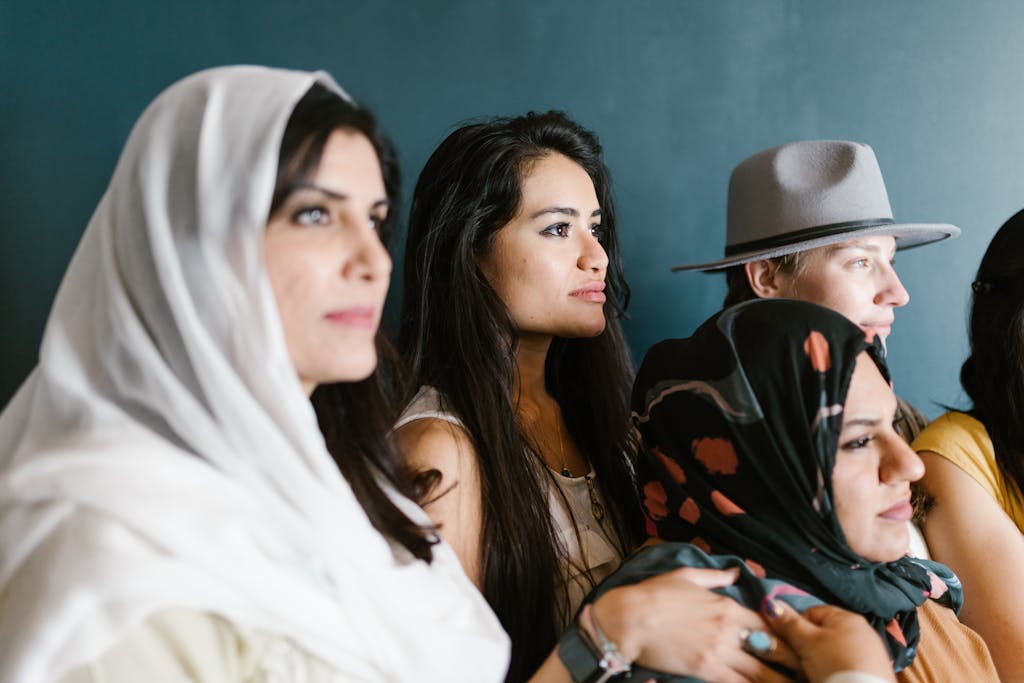 Diverse group of women wearing headscarves and hats, captured in an indoor setting.